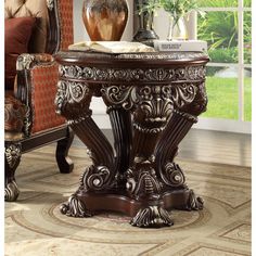 an ornately decorated end table in a living room with a couch and chair behind it