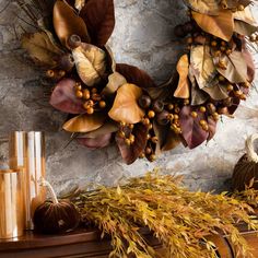 a wreath is hanging on the wall above a mantle with candles and other autumn decorations