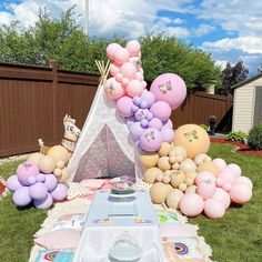 a teepee tent is set up in the yard with balloons and other decorations on it