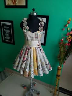 a dress made out of newspapers sitting on top of a table next to a vase with flowers