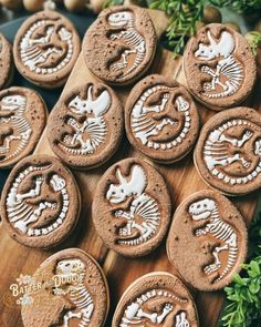 some cookies with white frosting are sitting on a wooden board next to green plants