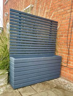 a blue bench sitting in front of a brick wall next to a green planter