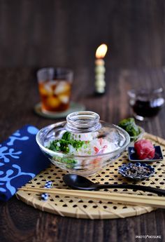 a glass bowl filled with food sitting on top of a table next to a candle