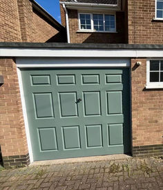 a green garage door in front of a brick house