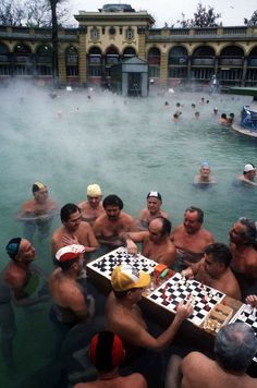 a group of men playing checkers in a hot pool with steam rising from the water