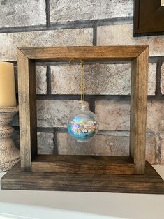 an ornament hanging from a wooden frame in front of a brick wall with candles