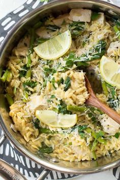 a skillet filled with pasta, asparagus and lemons on top of a table