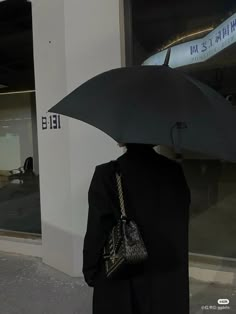 a woman holding an umbrella in front of a building