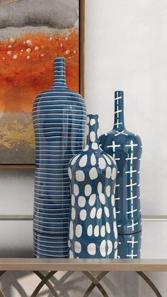 three vases sitting on top of a table next to each other in front of a painting