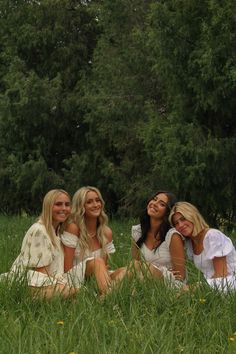 three beautiful young women sitting in the grass