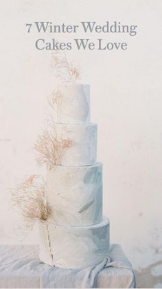 a three tiered white cake sitting on top of a table next to a wall