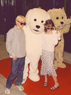 two children standing next to a giant polar bear and another child in sunglasses posing for the camera