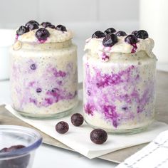 two jars filled with blueberries and yogurt sitting on top of a table