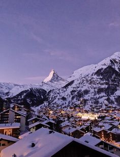 the mountains are covered in snow and lit up by lights at night, with houses below them