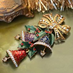 "During the 1940s, wearing a Christmas pin or corsage became a tradition of the season. I designed the Enamel Christmas Bells Pin with hidden joints to allow the bells and clappers to move independently, gently swinging from the crystal bow. Enameled in translucent royal blue, purple and crimson, each bell has a raised design and is edged in premium diamante crystal. The clappers tinkle merrily, set with large champagne color crystals. Blended blue-green enamel holly leaves are set with bright r Christmas Brooches, Christmas Bling, Tacky Christmas, Jewelry Christmas Tree, Holiday Pins, Holly Leaves, Sweet Romance, Pretty Christmas, Christmas Pins