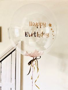 a clear balloon with the words happy birthday hanging from it's side on a wall