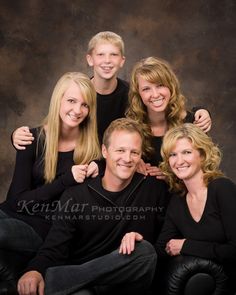 a group of people posing for a photo together in front of a dark background with one woman's arm around the other