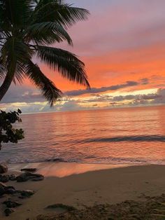 the sun is setting over the ocean with palm trees on the beach and waves coming in