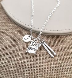 a silver necklace with two musical instruments and a smiley face on it, sitting next to a white purse