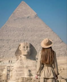 a woman wearing a hat standing in front of the great sphinx and giraffe