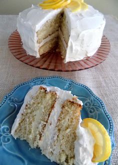 a slice of cake with white frosting and lemons on the side sitting on a blue plate