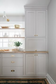 a kitchen with white cabinets and gold pulls on the cupboards is pictured in this image