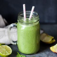 a green smoothie in a mason jar with two straws sticking out of the top