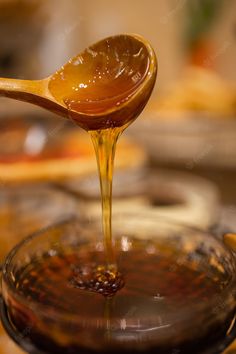 a spoon full of honey is being poured into a glass bowl with the liquid in it