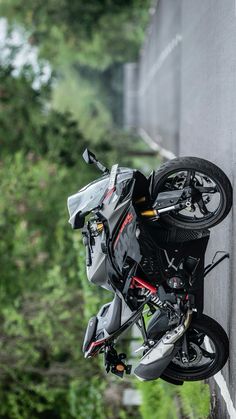 a motorcycle parked on the side of a road next to a tree lined street wall