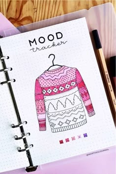 a notebook with an image of a sweater on it next to markers and marker pens