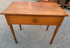 an old wooden table with one drawer on the top and two legs at the bottom