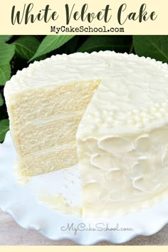 a white velvet cake on a plate with leaves in the background