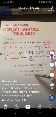 someone is holding a pen and writing on a piece of paper with korean words in it