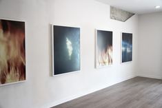 an empty room with three paintings hanging on the wall and wood flooring in front of it