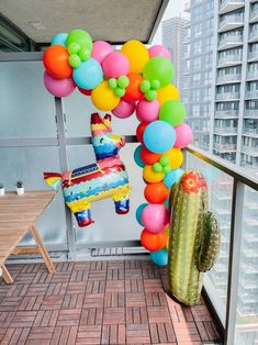 a balloon arch on top of a building next to a cactus and potted plant