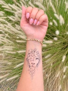 a woman's arm with a lion tattoo on it and flowers in the background