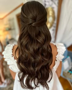 the back of a woman's head with long brown hair and curls in it