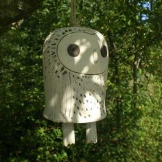 an owl shaped bird feeder hanging from a tree