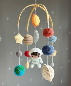 the mobile is made with crocheted balls and yarns, which are hanging from a string