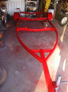 a large red piece of metal in a garage next to other tools and equipment on the floor