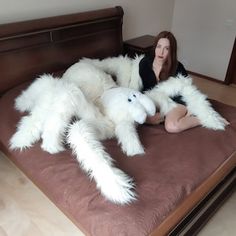 a woman sitting on top of a bed covered in giant white furry animal arms and legs