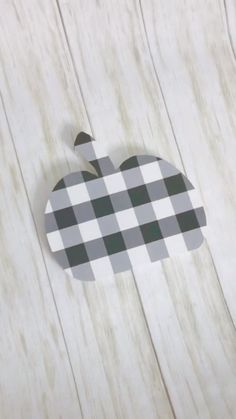 an apple cut out on the side of a wooden table with white and black checkered paper