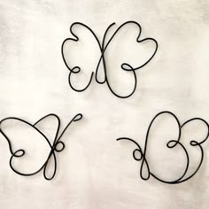 three metal butterfly sculptures sitting on top of a white wall