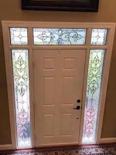 a white front door with stained glass panels on the top and bottom panel, next to a carpeted floor