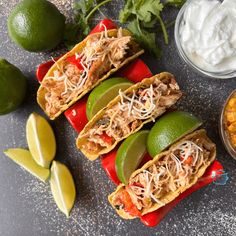 three tacos with shredded meat, avocado and sour cream on the side