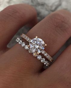 a woman's hand with two engagement rings on it and one diamond ring in the middle