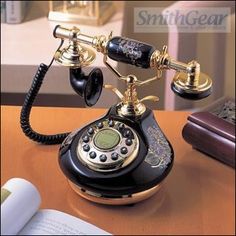 an old fashioned phone sitting on top of a table next to a book and pen