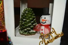 there is a snowman and a pine tree in the window sill with christmas decorations