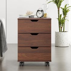 a wooden dresser with three drawers and a clock on top