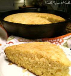 a piece of cornbread on a plate next to a skillet